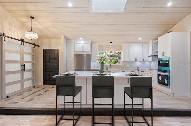 4916 Hidden Oaks Trl, Sarasota, FL 34232 - kitchen featuring freestanding refrigerator, a barn door, wood ceiling, light countertops, and white cabinetry