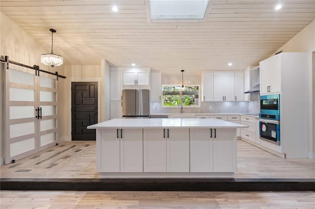 4916 Hidden Oaks Trl, Sarasota, FL 34232 - kitchen featuring freestanding refrigerator, a barn door, wood ceiling, a center island, and light wood-type flooring