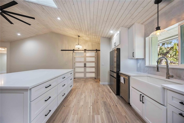 4916 Hidden Oaks Trl, Sarasota, FL 34232 - kitchen featuring appliances with stainless steel finishes, a barn door, light countertops, light wood-style flooring, and a sink