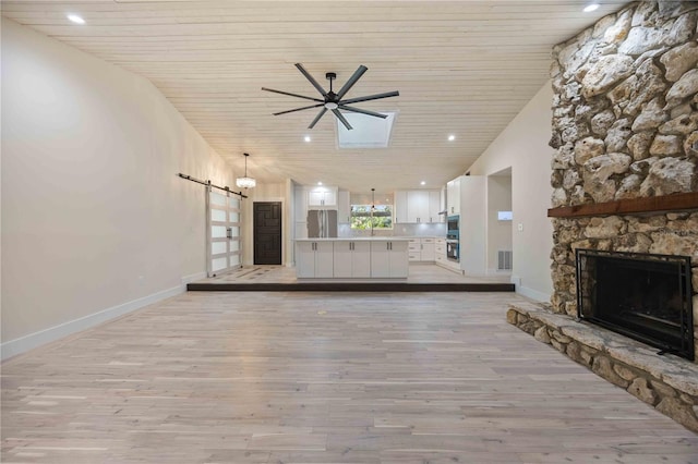 4916 Hidden Oaks Trl, Sarasota, FL 34232 - unfurnished living room featuring a barn door, light wood finished floors, wood ceiling, ceiling fan, and a fireplace