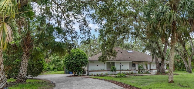 4916 Hidden Oaks Trl, Sarasota, FL 34232 - view of front of property featuring curved driveway, a front lawn, a shingled roof, and stucco siding