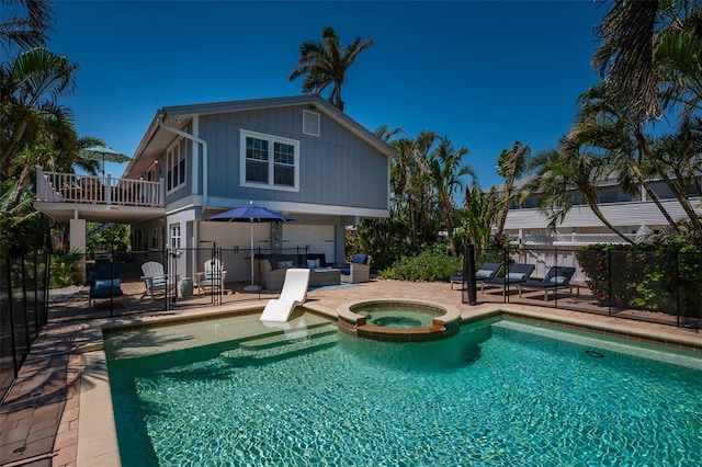 view of swimming pool featuring a patio area, a pool with connected hot tub, and fence