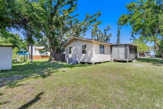 rear view of property with fence, a sunroom, and a yard