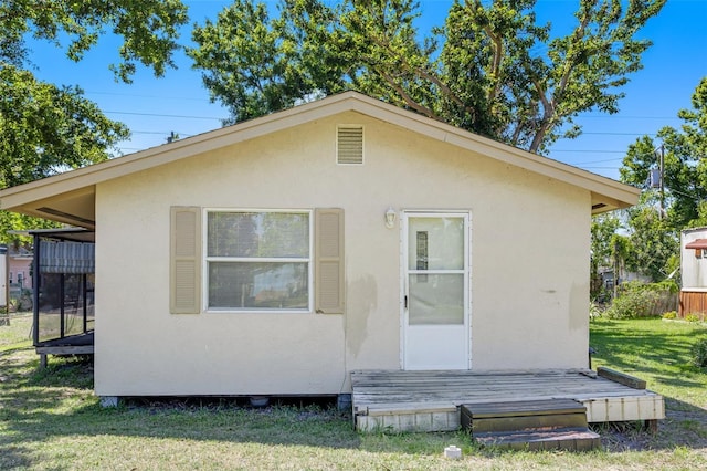rear view of house with a lawn and stucco siding