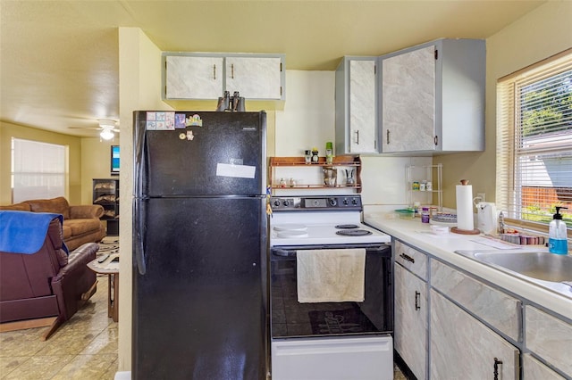 kitchen featuring light countertops, a ceiling fan, freestanding refrigerator, electric range, and open floor plan