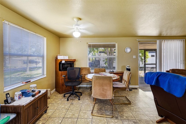 dining area with a textured ceiling, a ceiling fan, baseboards, and light tile patterned floors
