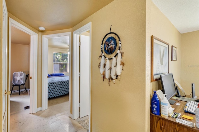 hallway with a textured wall and light tile patterned floors