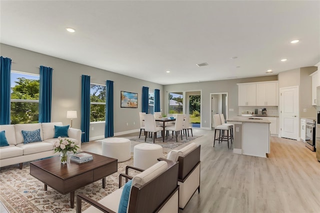 living room with baseboards, visible vents, light wood-type flooring, and recessed lighting