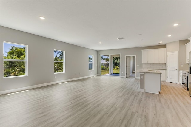 unfurnished living room with light wood-style flooring, a wealth of natural light, and recessed lighting