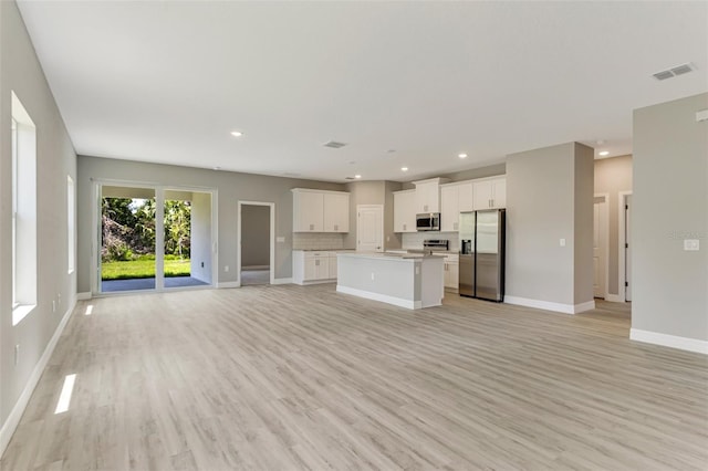 unfurnished living room featuring baseboards, light wood-style floors, visible vents, and recessed lighting