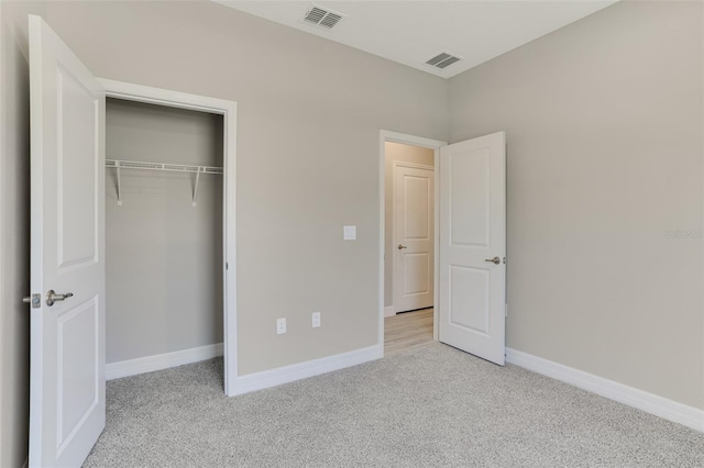 unfurnished bedroom with light carpet, baseboards, visible vents, and a closet