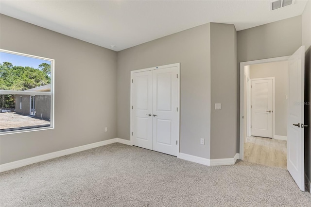 unfurnished bedroom featuring a closet, carpet, visible vents, and baseboards