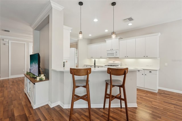 5023 Brickell Park Cv, Bradenton, FL 34211 - kitchen featuring white microwave, stove, a breakfast bar, wood finished floors, and a peninsula