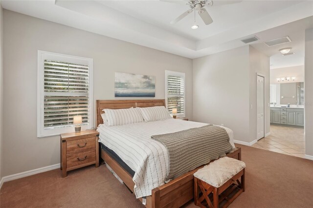 5023 Brickell Park Cv, Bradenton, FL 34211 - bedroom with light colored carpet, baseboards, a raised ceiling, ensuite bath, and ceiling fan