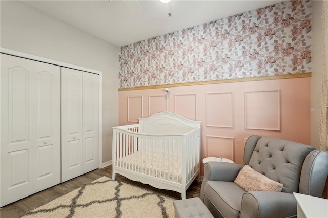 5023 Brickell Park Cv, Bradenton, FL 34211 - bedroom featuring a wainscoted wall, a closet, a nursery area, wood finished floors, and wallpapered walls