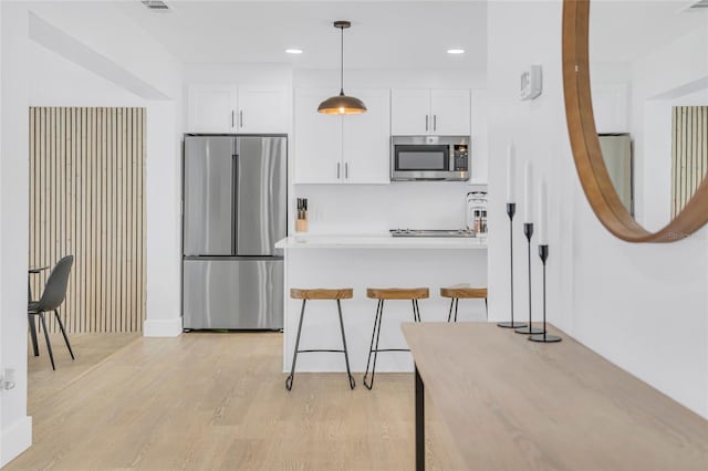 1921 Fern Ave, Sarasota, FL 34235 - kitchen with light wood finished floors, stainless steel appliances, hanging light fixtures, and white cabinets