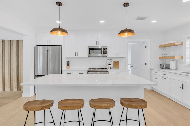 1921 Fern Ave, Sarasota, FL 34235 - kitchen with stainless steel appliances, a breakfast bar, open shelves, visible vents, and light wood finished floors