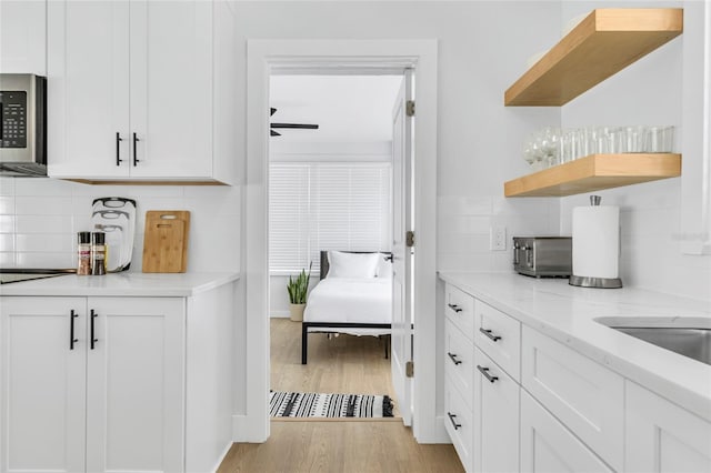 1921 Fern Ave, Sarasota, FL 34235 - bar featuring light wood-style floors, decorative backsplash, ceiling fan, and stainless steel microwave