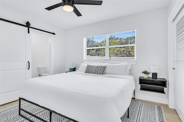 1921 Fern Ave, Sarasota, FL 34235 - bedroom with a barn door, light wood-type flooring, a ceiling fan, and a closet