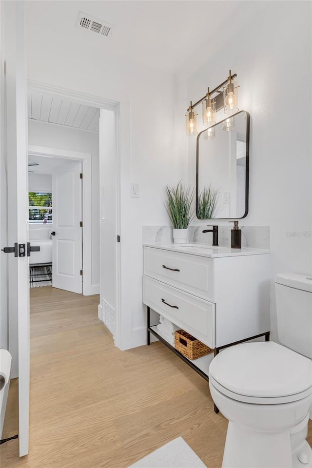 1921 Fern Ave, Sarasota, FL 34235 - bathroom featuring vanity, toilet, visible vents, and wood finished floors