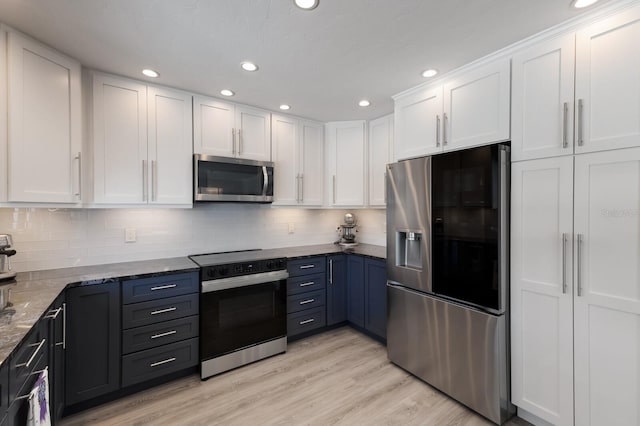 508 70th St, Holmes Beach, FL 34217 - kitchen with stainless steel appliances, white cabinets, dark stone counters, and decorative backsplash