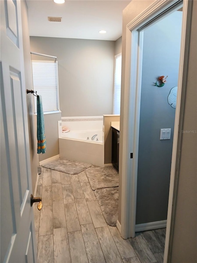 6631 63rd Ter E, Bradenton, FL 34203 - bathroom with a garden tub, wood finished floors, vanity, recessed lighting, and baseboards