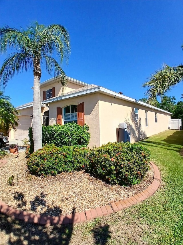 6631 63rd Ter E, Bradenton, FL 34203 - view of side of home with stucco siding, a lawn, and an attached garage