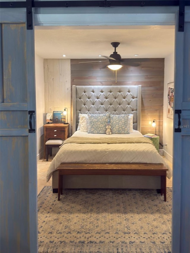 carpeted bedroom with wood walls and a barn door