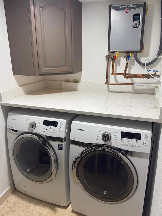 washroom with washer and dryer, light tile patterned floors, cabinet space, and water heater