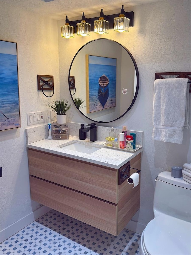 bathroom with toilet, a textured wall, and vanity