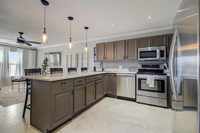 kitchen featuring a peninsula, a textured ceiling, a sink, and appliances with stainless steel finishes