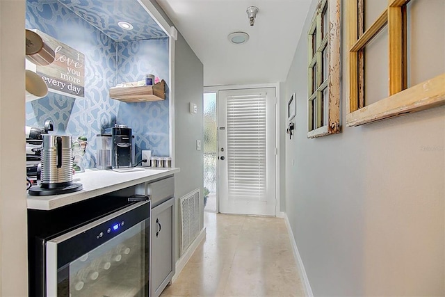 hallway featuring visible vents, baseboards, and wine cooler
