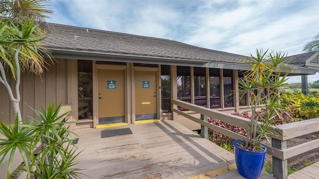 view of exterior entry with roof with shingles