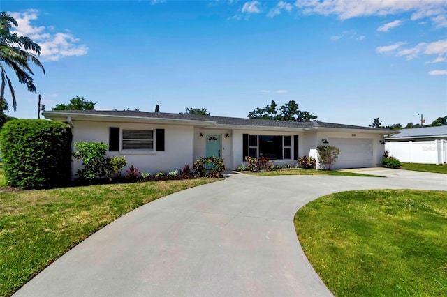 single story home with concrete driveway, an attached garage, a front yard, and stucco siding