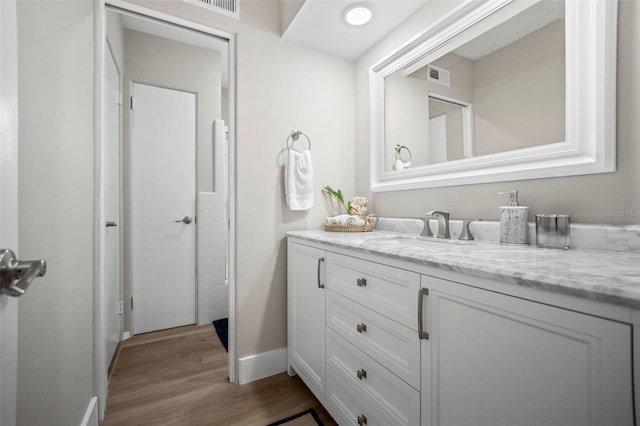bathroom featuring baseboards, vanity, wood finished floors, and visible vents