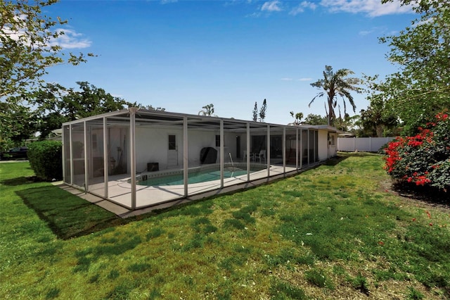 rear view of property featuring a lawn, a patio, fence, and an outdoor pool