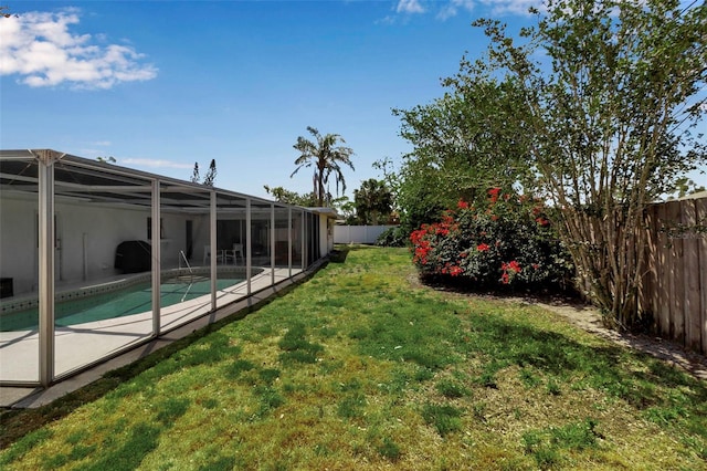 view of yard featuring glass enclosure, a fenced in pool, and a fenced backyard