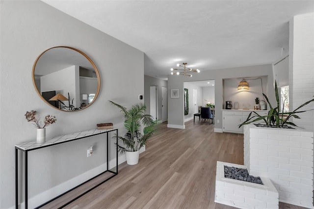 interior space featuring baseboards, a chandelier, and light wood finished floors