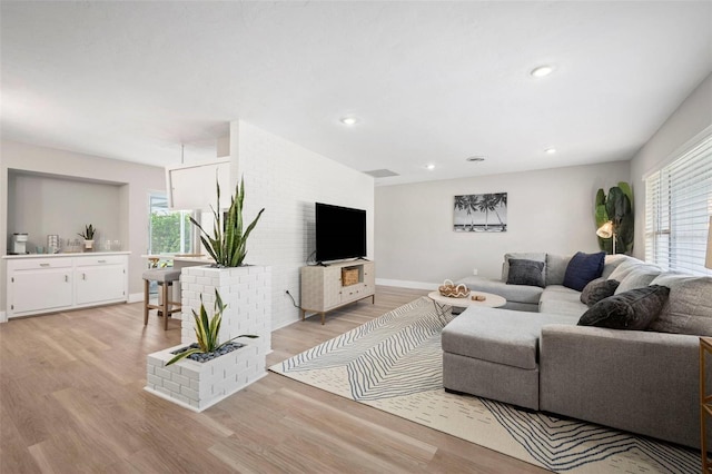 living area with a healthy amount of sunlight, baseboards, and light wood finished floors