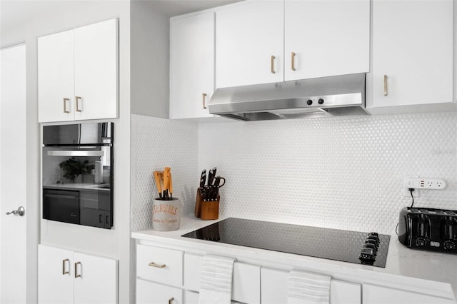 kitchen with wall oven, backsplash, under cabinet range hood, and white cabinets