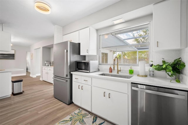 kitchen with light countertops, a sink, decorative backsplash, and stainless steel appliances