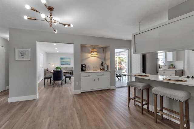 kitchen featuring a sink, light countertops, light wood finished floors, and white cabinetry
