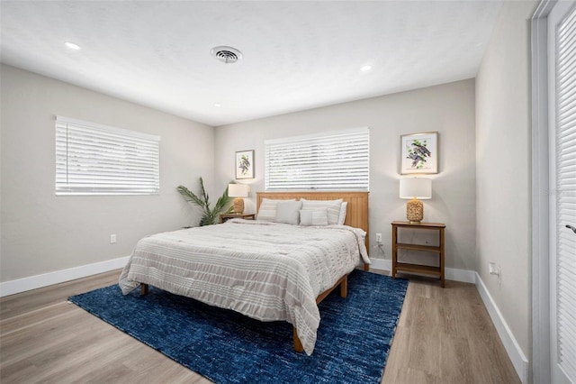 bedroom with baseboards, recessed lighting, wood finished floors, and visible vents