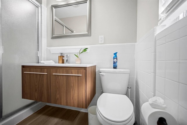 full bath featuring vanity, wood finished floors, toilet, tile walls, and a stall shower
