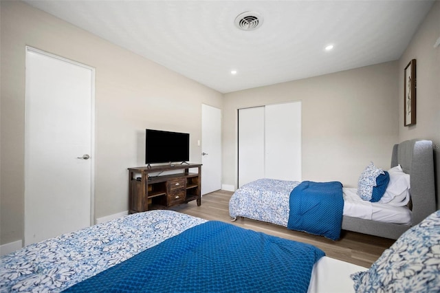 bedroom with visible vents, recessed lighting, wood finished floors, and a closet