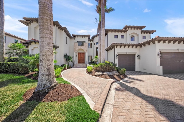 5830 Jamila River Dr, Venice, FL 34293 - mediterranean / spanish-style house with stucco siding, an attached garage, decorative driveway, and a tiled roof