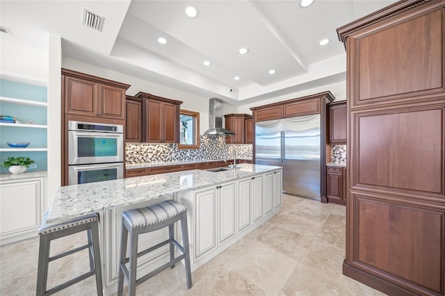 5830 Jamila River Dr, Venice, FL 34293 - kitchen with visible vents, decorative backsplash, light stone counters, wall chimney range hood, and appliances with stainless steel finishes