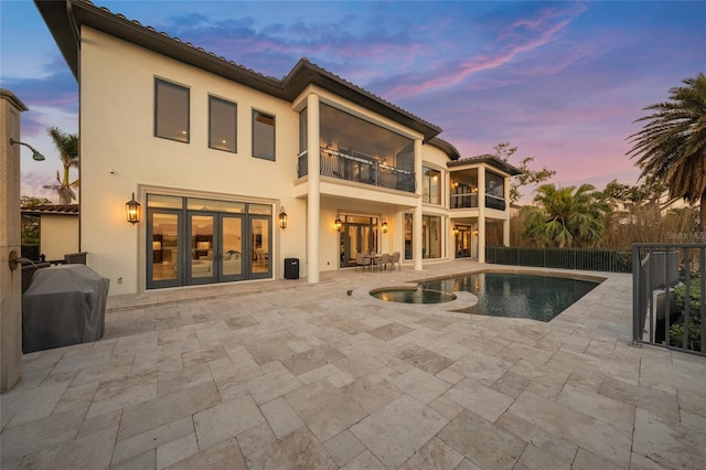 5830 Jamila River Dr, Venice, FL 34293 - back of property at dusk featuring french doors, a tiled roof, a balcony, a patio, and stucco siding