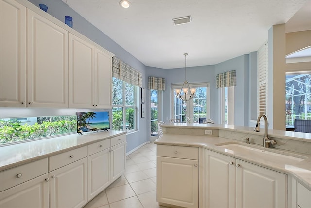 7528 Ascot Ct, Bradenton, FL 34201 - kitchen with a sink, a chandelier, light countertops, light tile patterned flooring, and white cabinetry