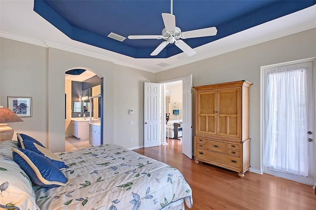 7528 Ascot Ct, Bradenton, FL 34201 - bedroom featuring a tray ceiling, arched walkways, light wood finished floors, crown molding, and baseboards